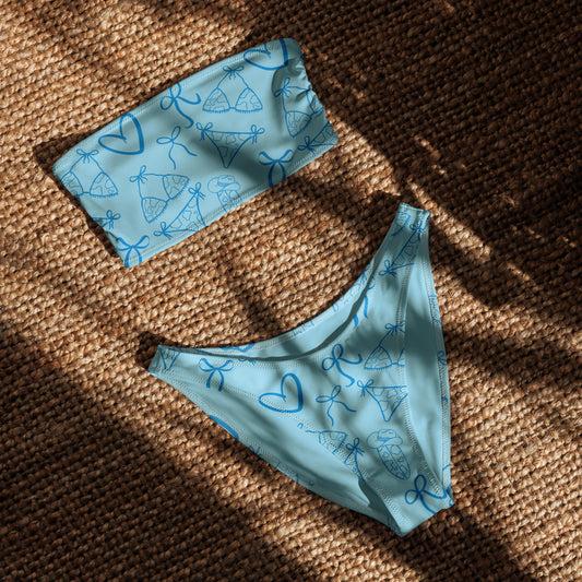 Woman wearing the Vibewear 'Blue Crush' bandeau bikini set, which features a vibrant blue abstract pattern, a strapless top, and flattering high-leg bottoms.