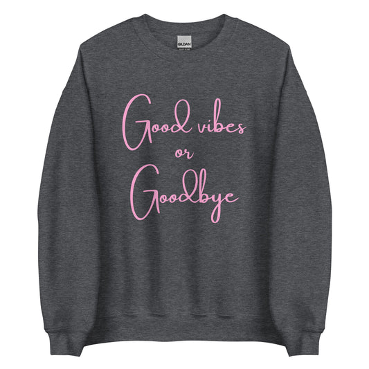 The 'Good Vibes or Goodbye' classic sweatshirt shown in dark grey, with the bold slogan printed in a pink retro-style font across the chest.