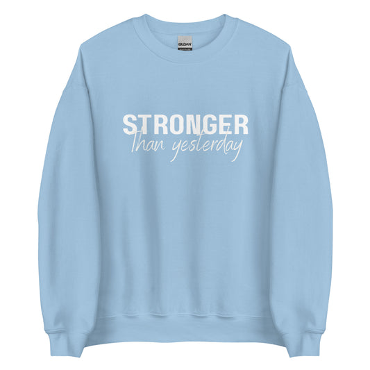 The 'Stronger Than Yesterday' classic sweatshirt shown in light blue, with the motivational slogan printed in a bold, white, distressed font across the chest.