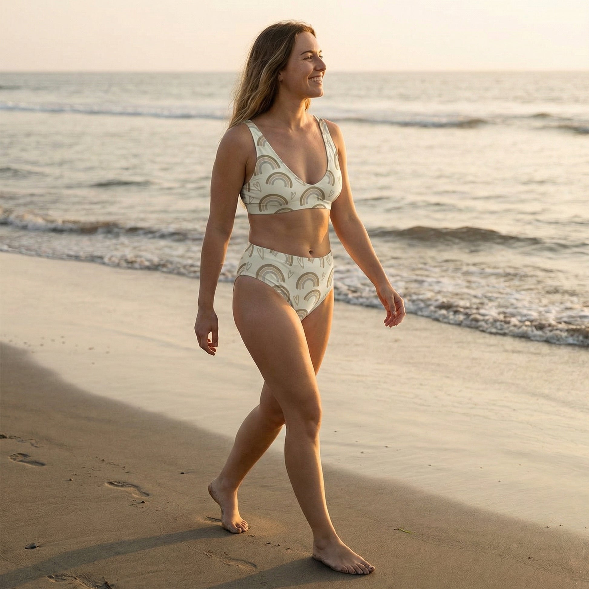 Woman in a patterned bikini walking on a beach at sunset.