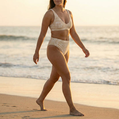 Woman in a beige bikini walking on a beach at sunset