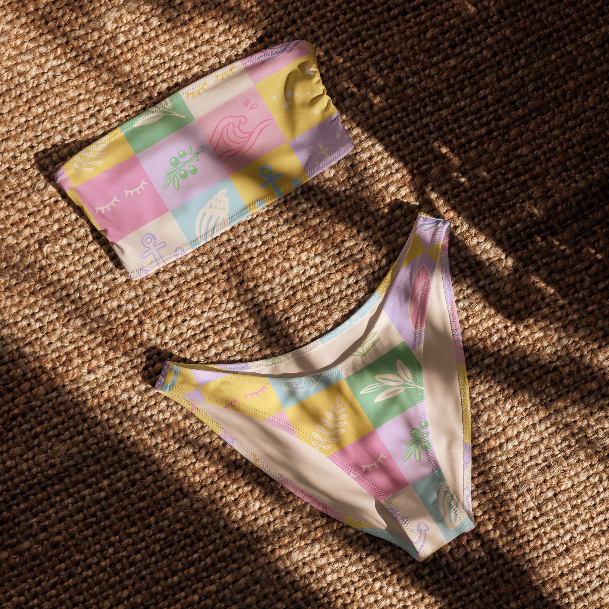 Recycled bandeau bikini with pastel patchwork pattern laid flat on woven mat