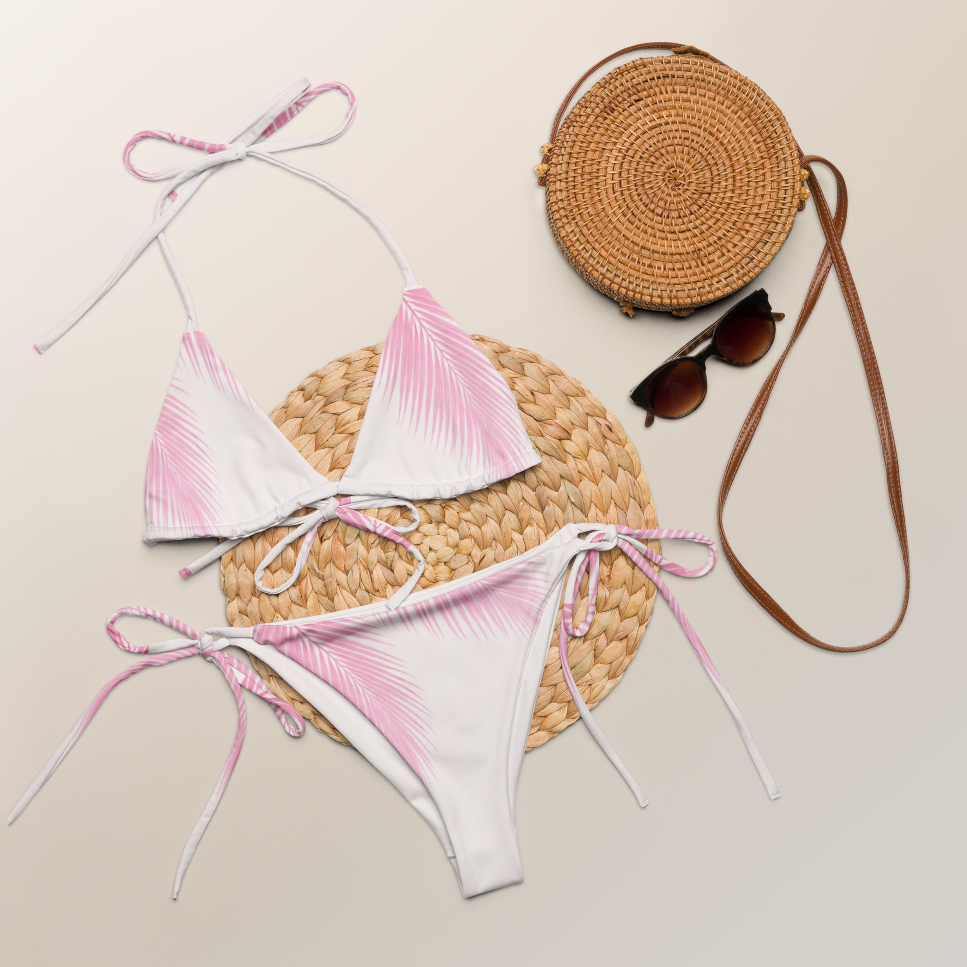 Pink Palm Glow recycled string bikini laid flat with summer accessories