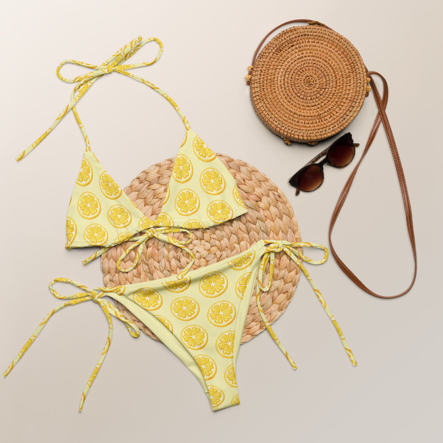 Yellow citrus print recycled string bikini laid flat with summer accessories