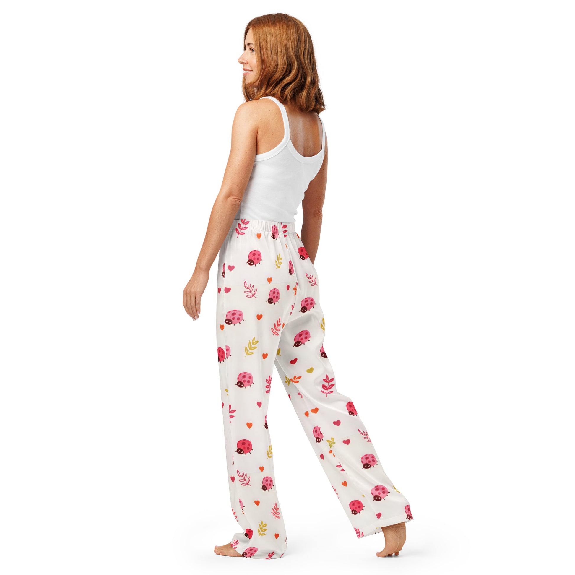Woman wearing the Vibewear 'Ladybird Daydream' satin pajama pants, highlighting the cute red ladybug pattern and the relaxed, straight-leg fit.