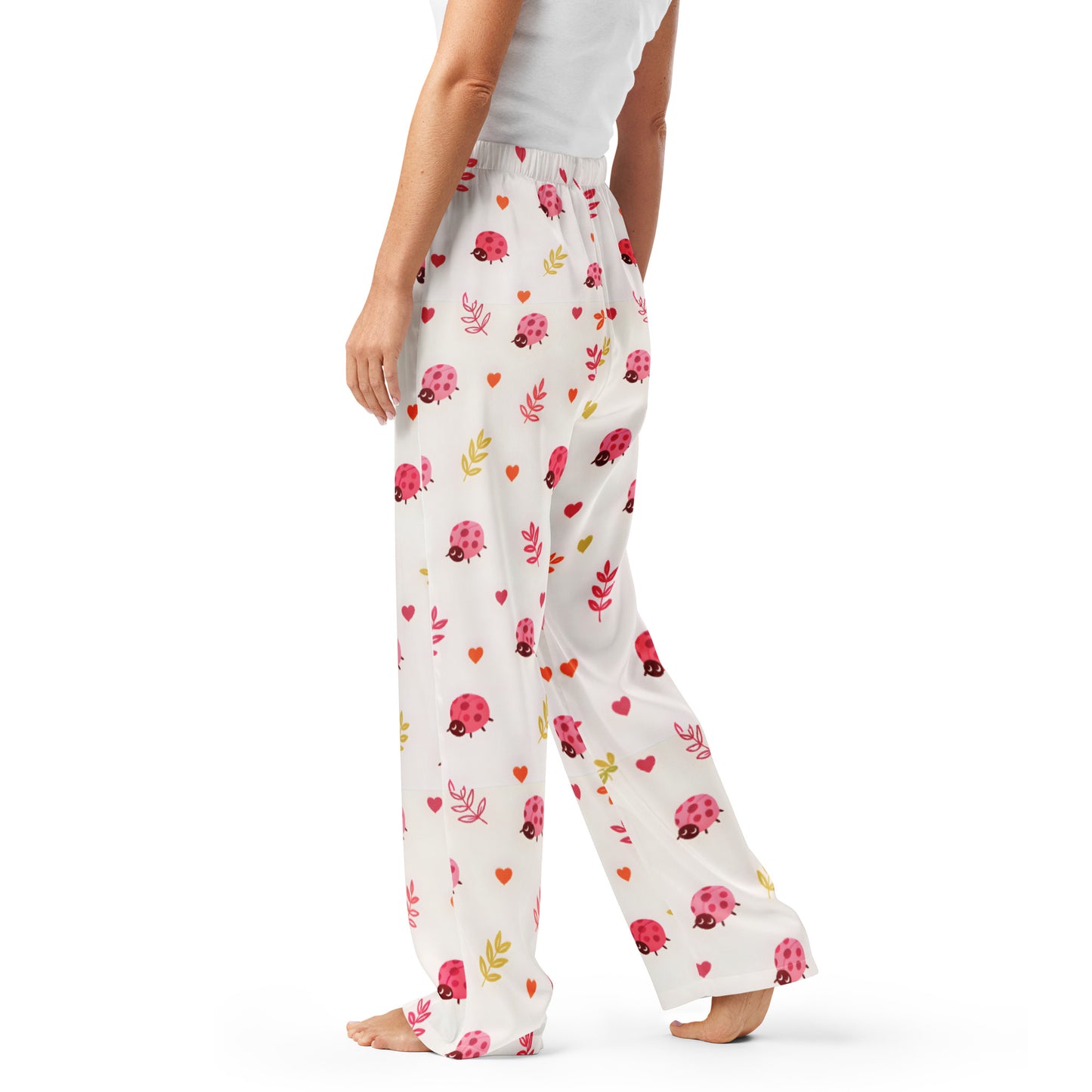 Woman wearing the Vibewear 'Ladybird Daydream' satin pajama pants, highlighting the cute red ladybug pattern and the relaxed, straight-leg fit.