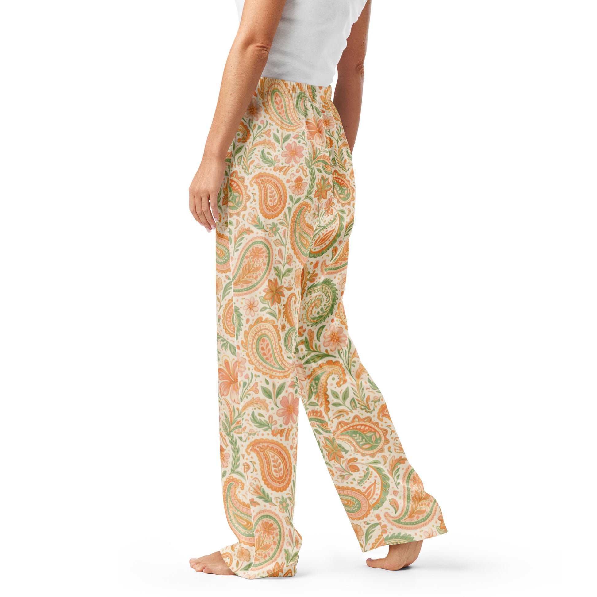 Woman wearing the Vibewear 'Vintage Palm' satin pajama pants, highlighting the green and orange tropical leaf pattern and the relaxed, straight-leg fit.