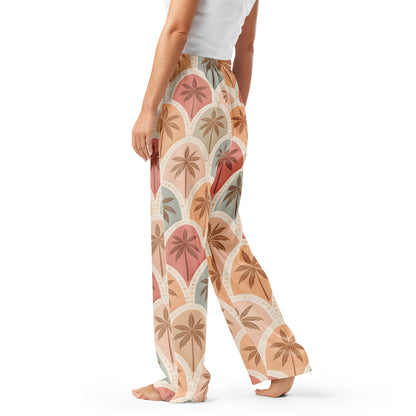 Woman wearing the Vibewear 'Sunset Palm Mosaic' satin pajama pants, highlighting the intricate blue and orange geometric pattern and the relaxed, straight-leg fit.