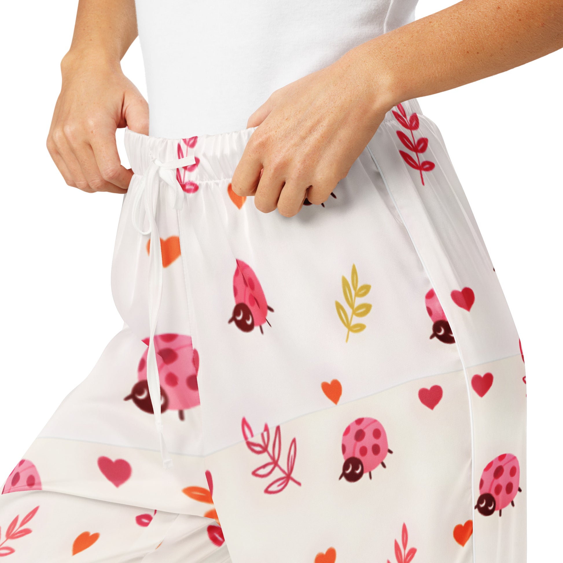 Woman wearing the Vibewear 'Ladybird Daydream' satin pajama pants, highlighting the cute red ladybug pattern and the relaxed, straight-leg fit.