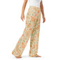 Woman wearing the Vibewear 'Vintage Palm' satin pajama pants, highlighting the green and orange tropical leaf pattern and the relaxed, straight-leg fit.