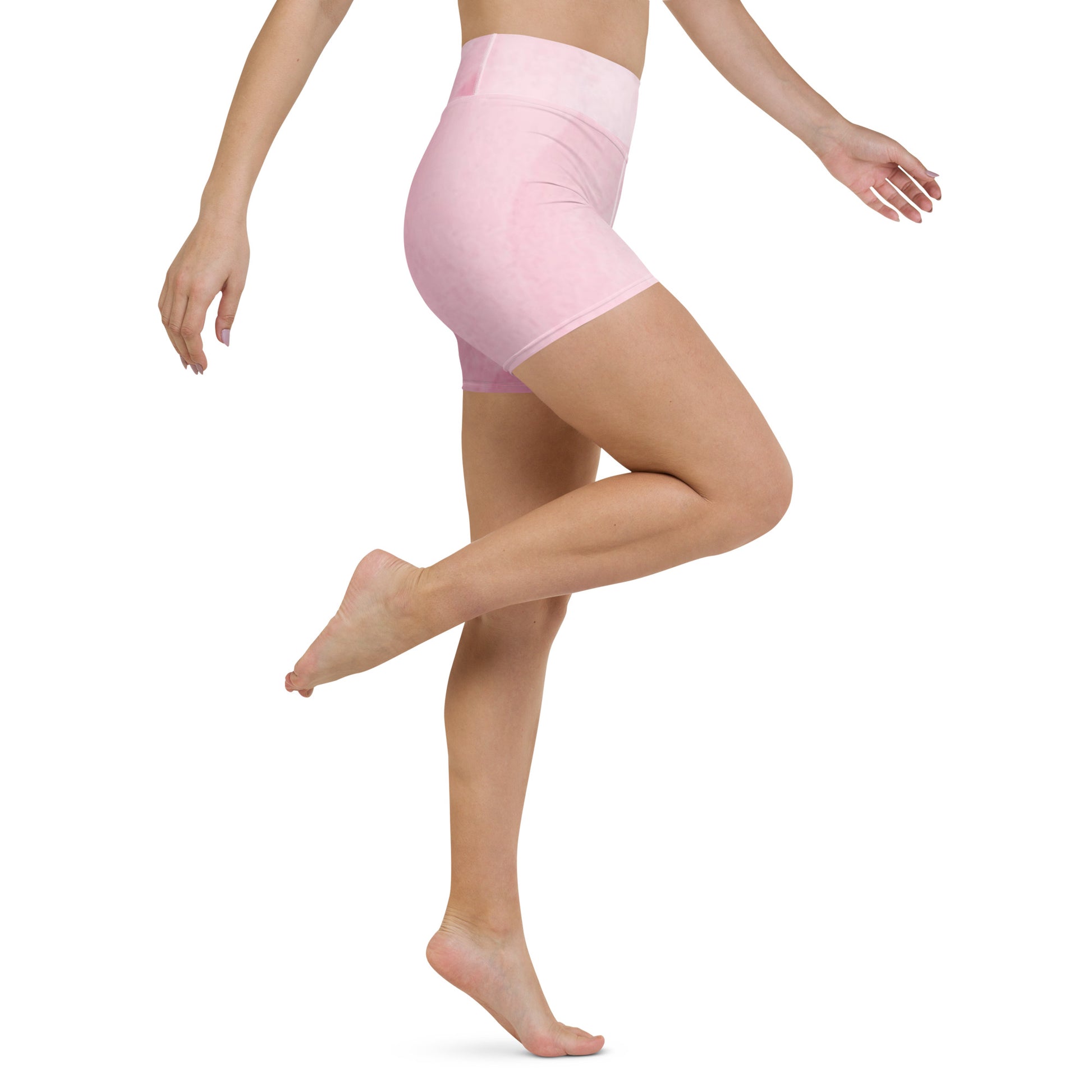 Model wearing pink high waist yoga shorts lifting leg to show flexibility and comfort