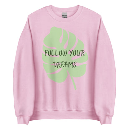 The 'Follow Your Dreams' classic sweatshirt shown in light pink, with the motivational slogan printed in a white script and sans-serif font across the chest.