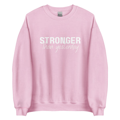 The 'Stronger Than Yesterday' classic sweatshirt shown in light pink, with the motivational slogan printed in a bold, white, distressed font across the chest.